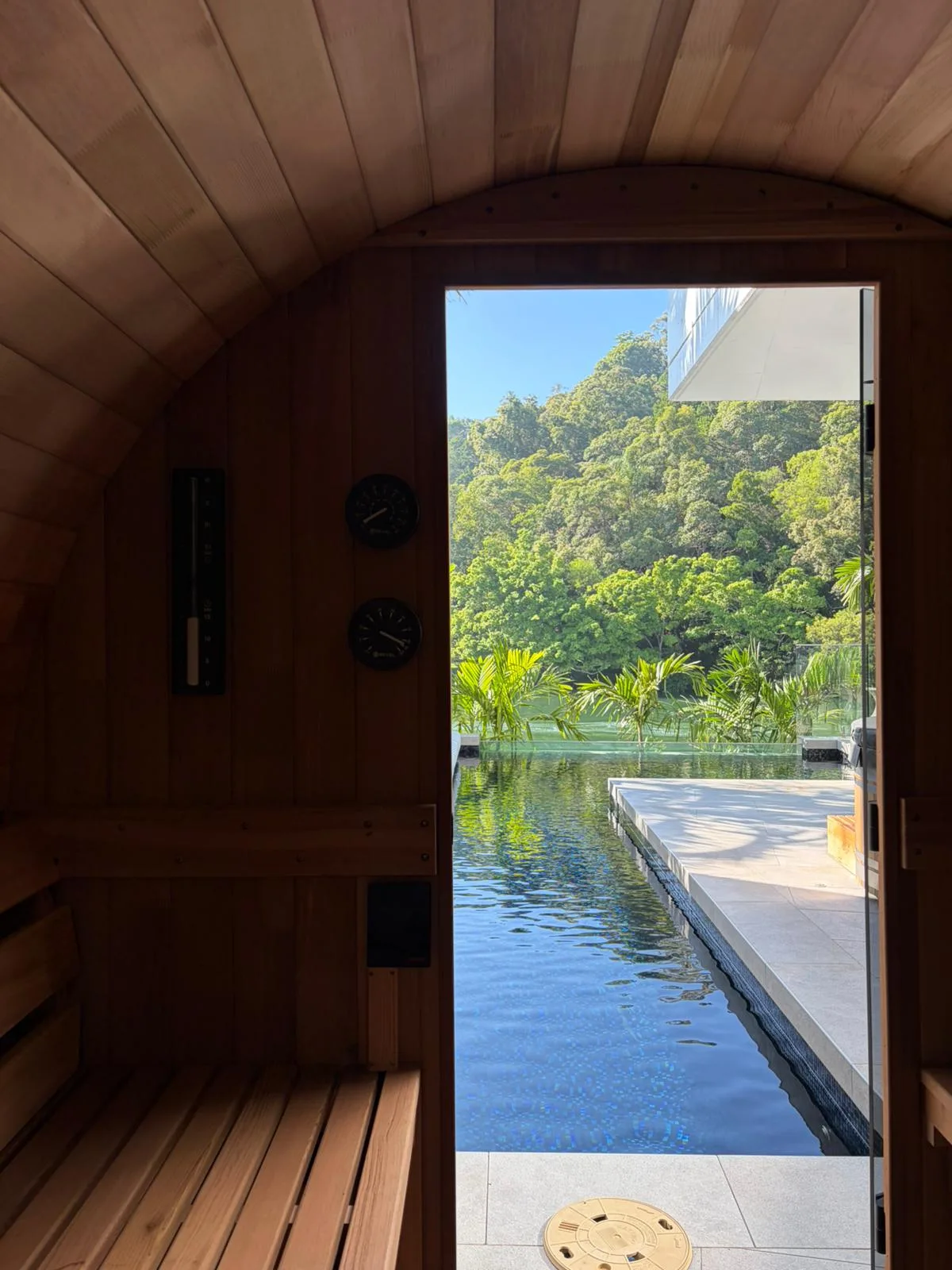 Cedar barrel sauna view through the opening toward the pool