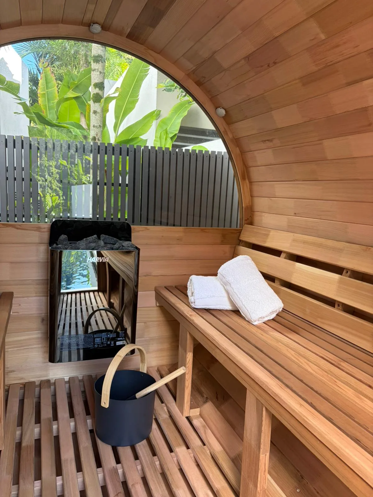 Cedar barrel sauna interior with towels and pool view