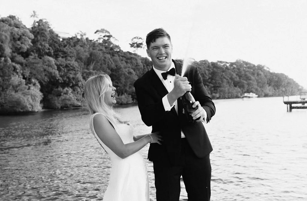 Couple with champagne on the jetty, river behind