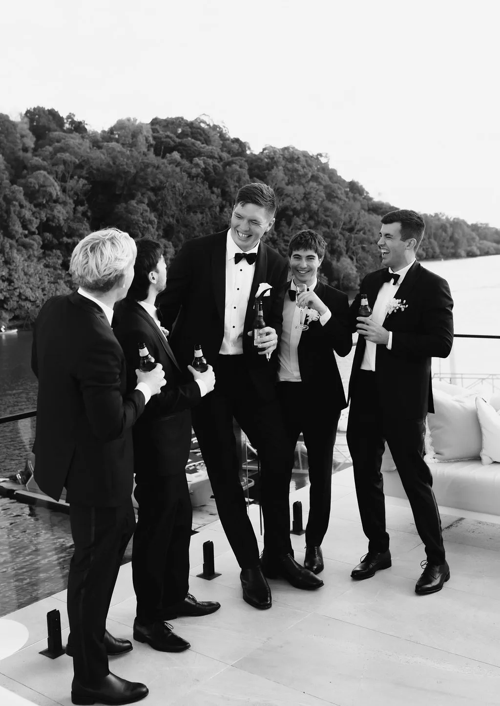 Groomsmen laughing on the jetty with river behind