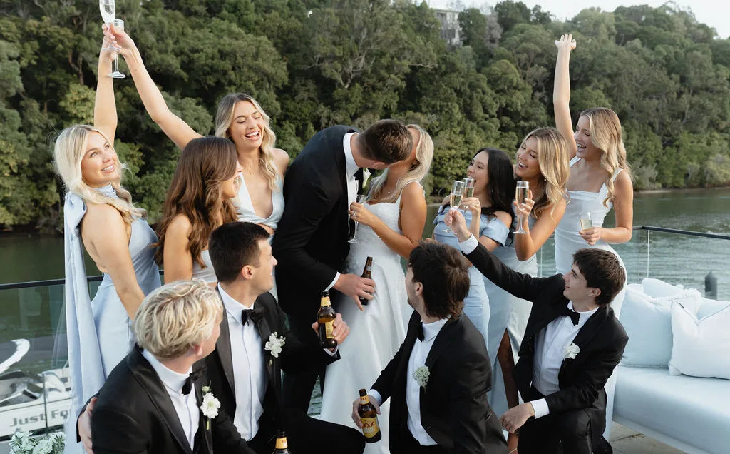 Guests cheersing on the jetty at sunset with the Noosa River behind